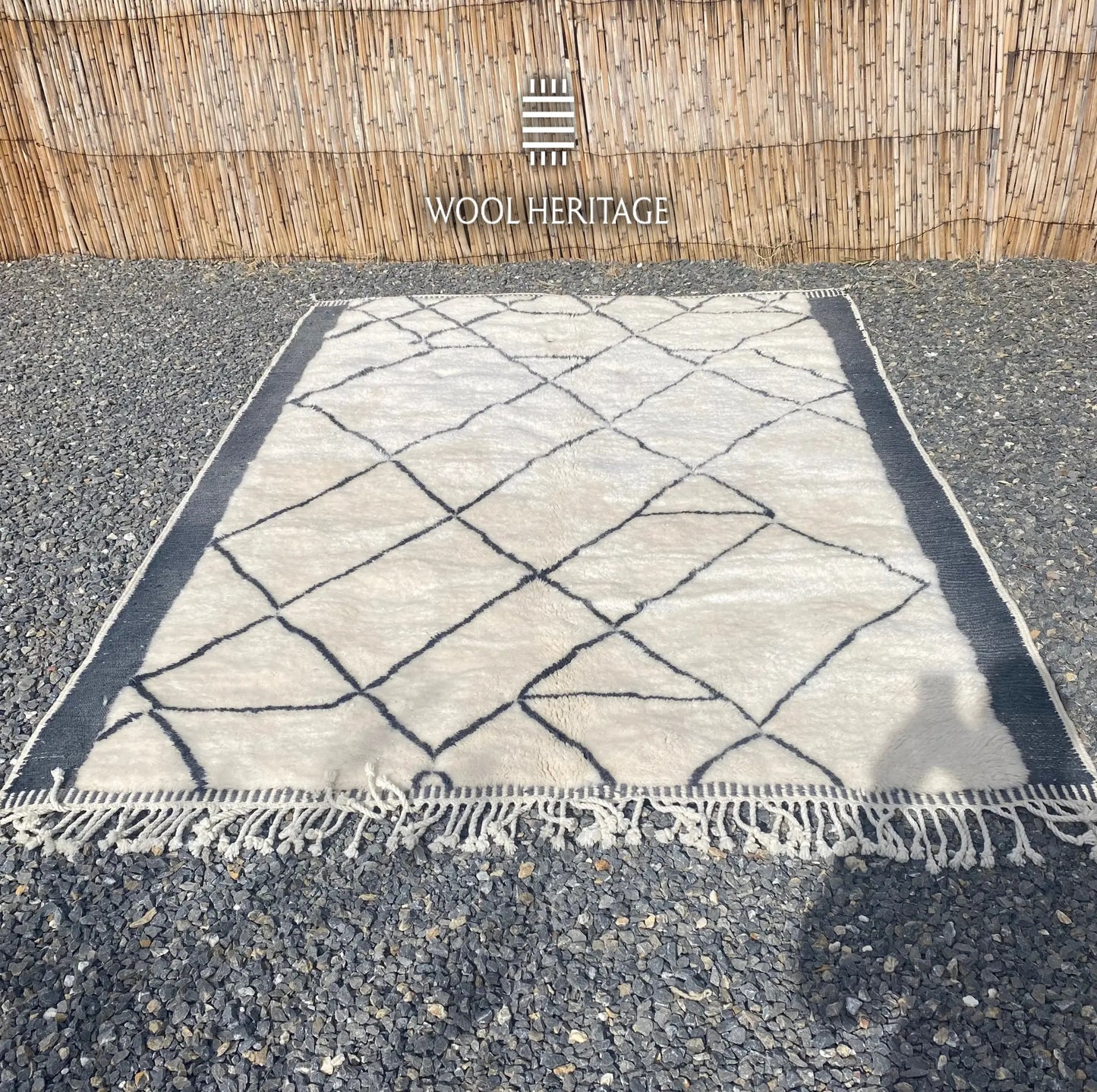 ADRAR Beni Mrirt rug laid flat, showing its complete charcoal mountain-like geometry across a warm ivory field