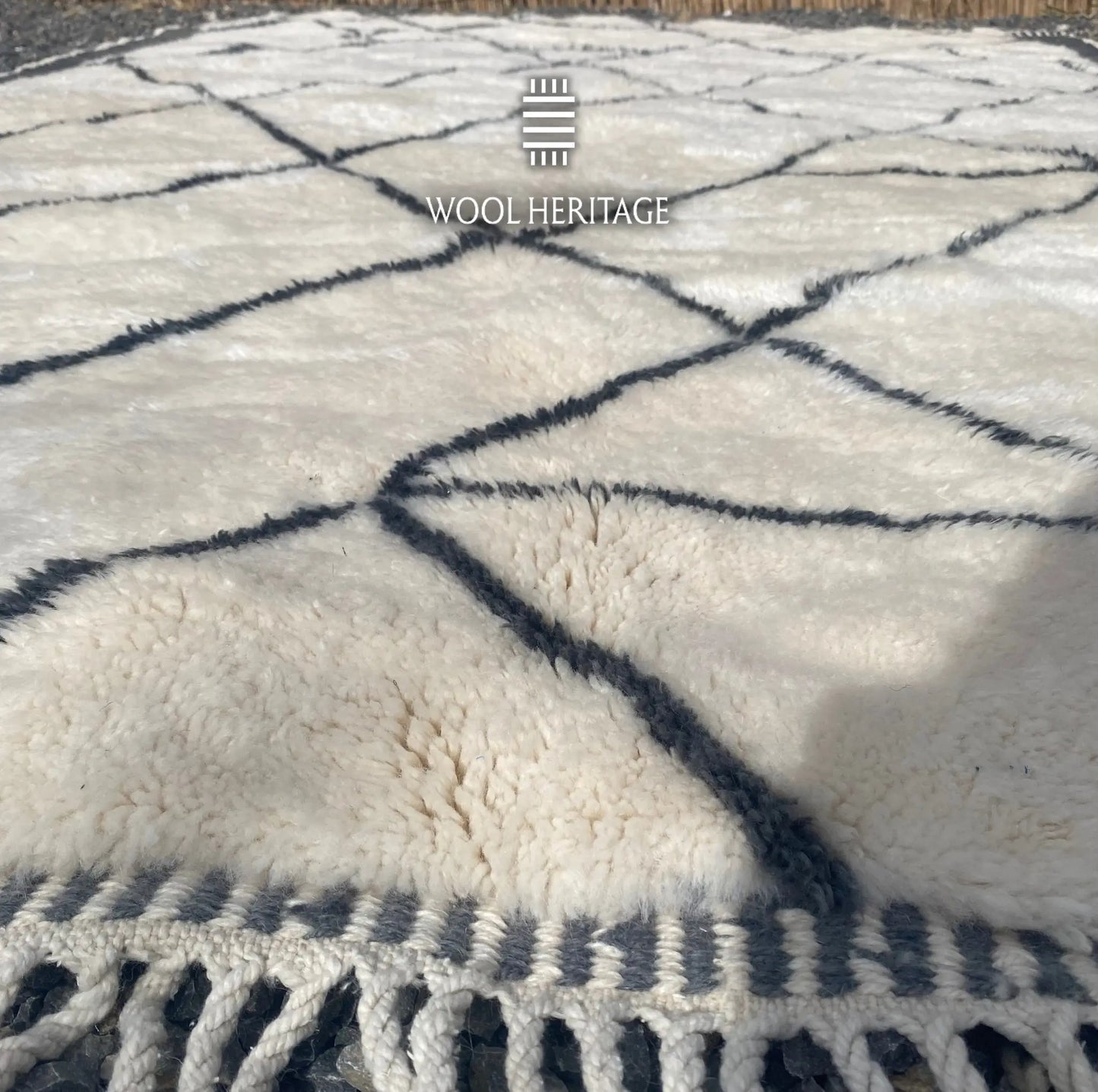 Close-up of ADRAR rug showing its soft ivory Moroccan wool pile and hand-drawn charcoal geometric lines