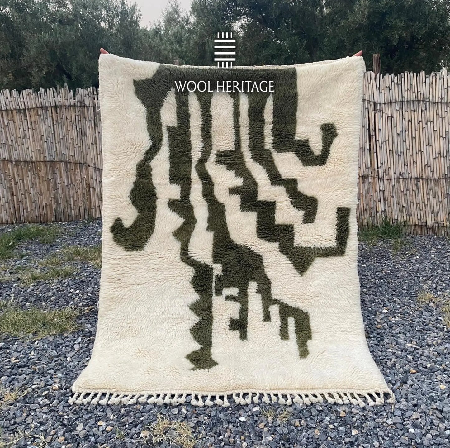 AKNARI hand-knotted ivory and olive Moroccan wool rug displayed outdoors in a full front view