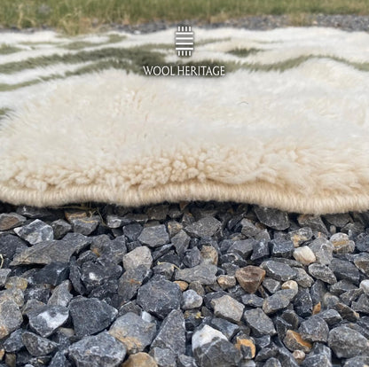 Close-up of AKNARI rug showing its soft ivory Moroccan wool pile, olive pattern, and finished edge
