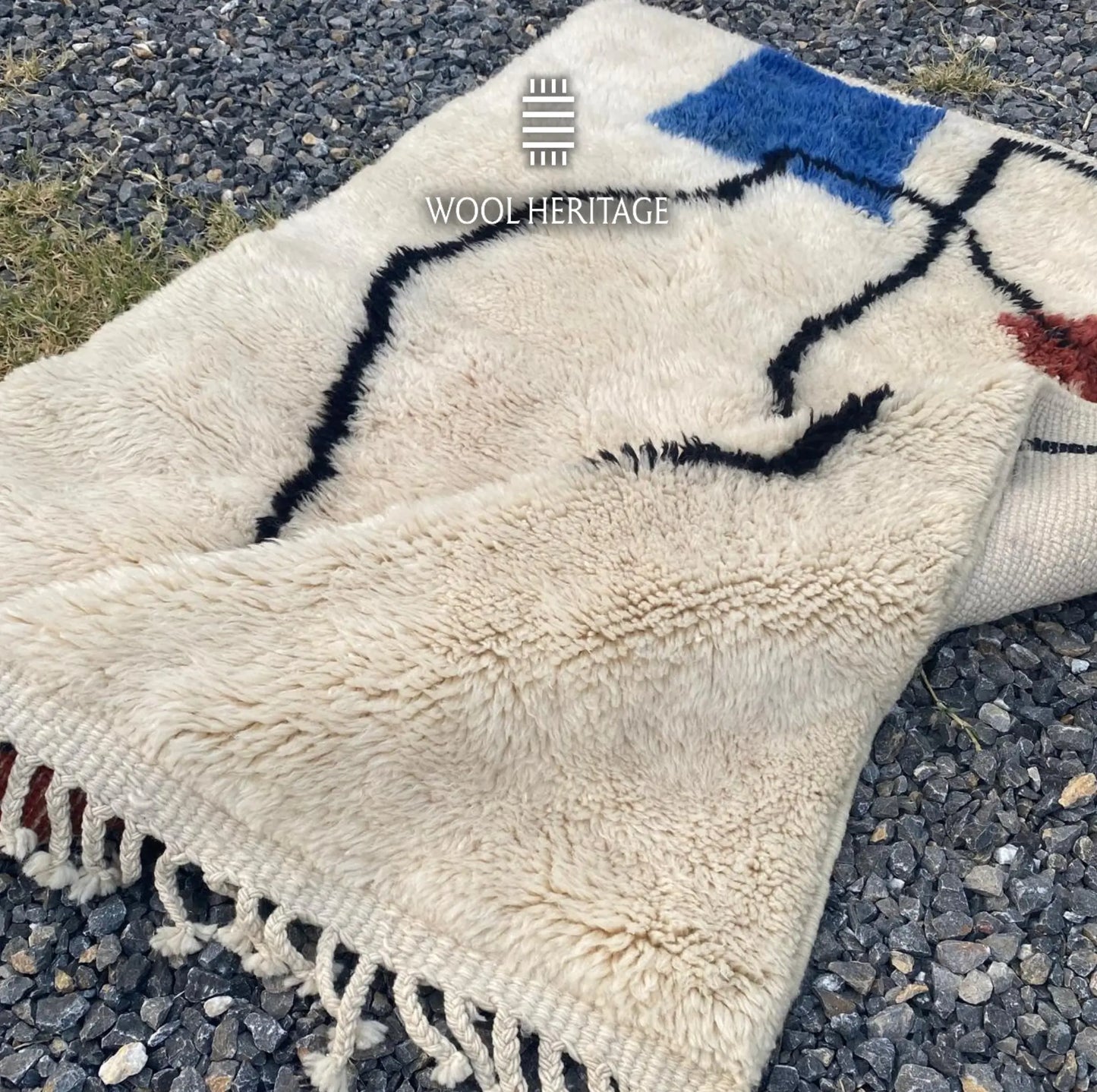 Folded detail of AMARG Moroccan rug showing the cobalt-blue form and expressive black contours on ivory wool