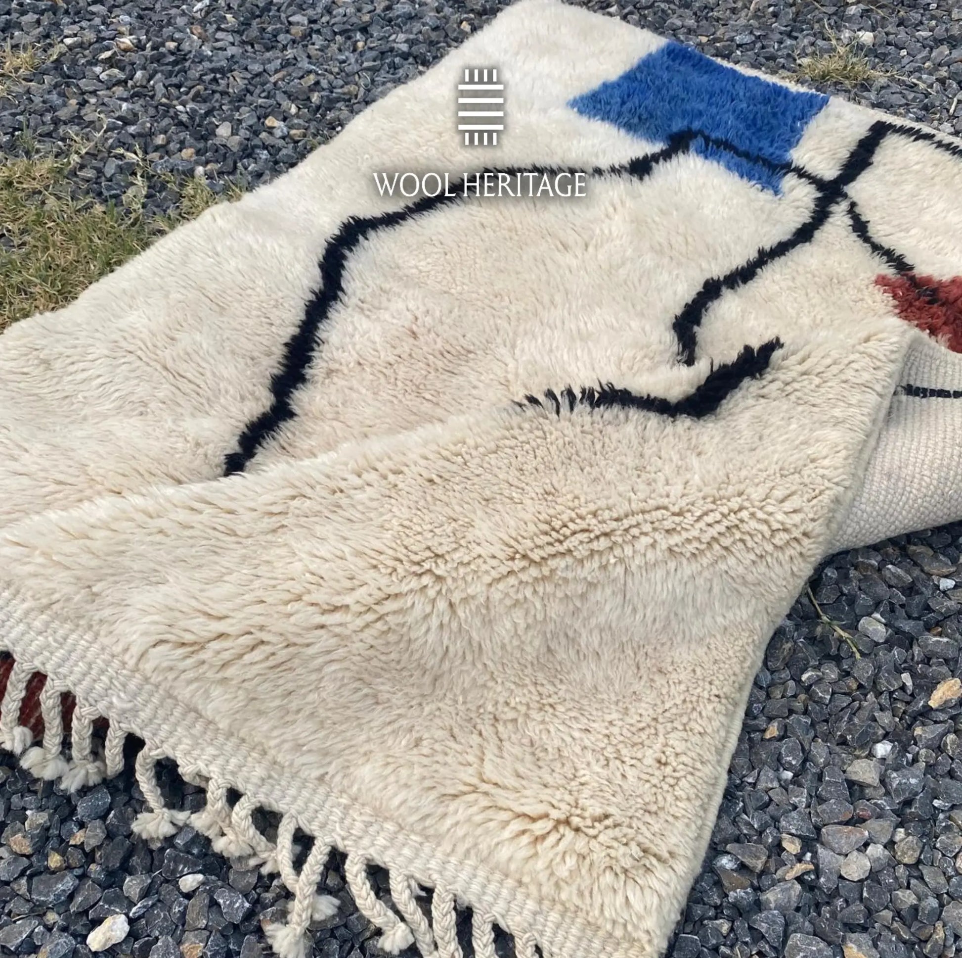 Folded detail of AMARG Moroccan rug showing the cobalt-blue form and expressive black contours on ivory wool