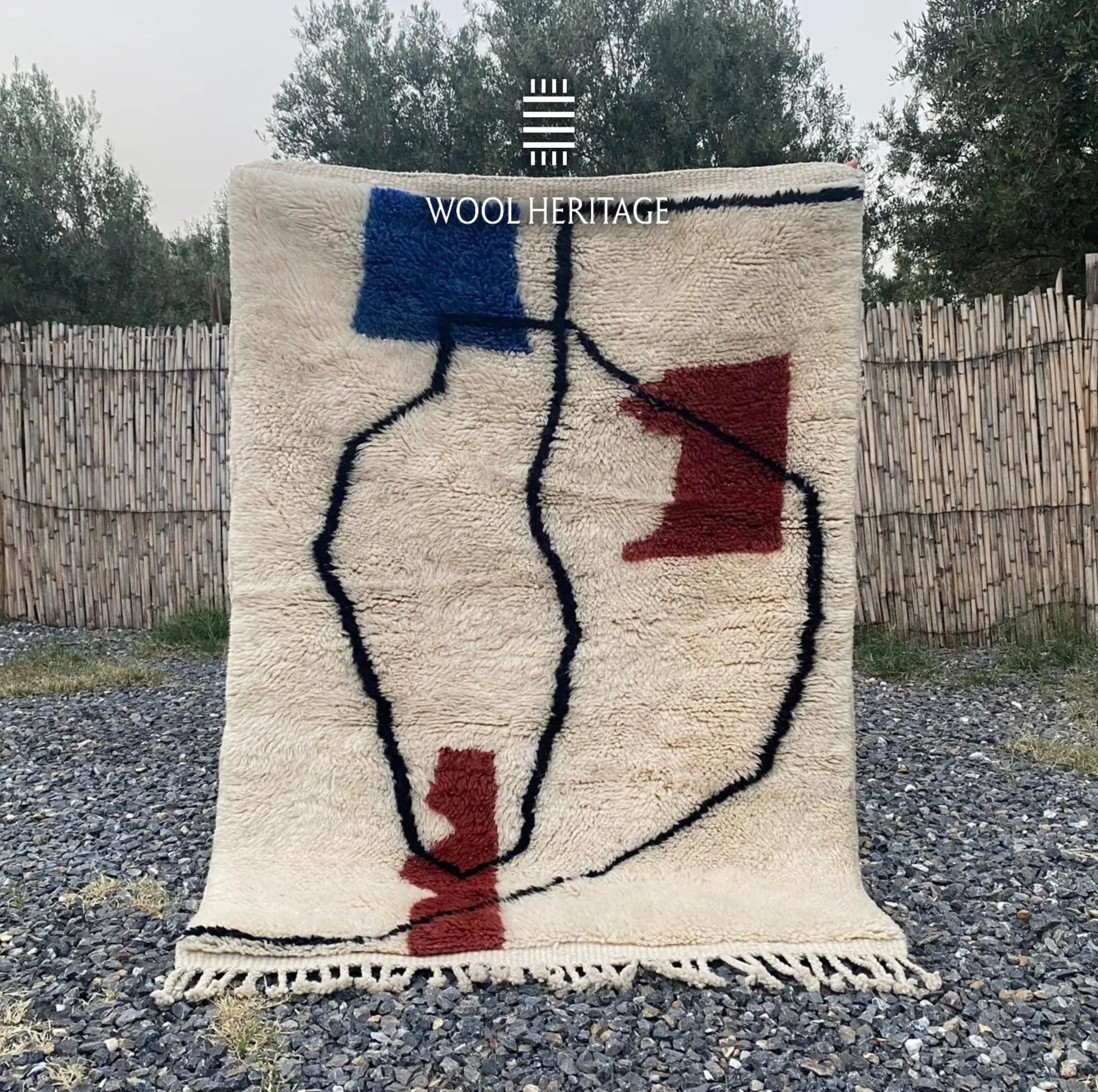 AMARG hand-knotted ivory Moroccan wool rug displayed outdoors with black contours and blue and burgundy forms