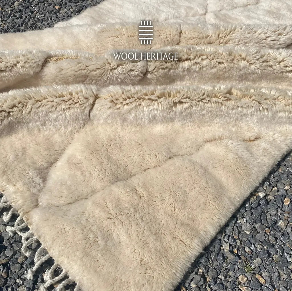 Folded detail of AMLAL hand-knotted rug showing its ivory pile, geometric linework, and hand-finished fringe