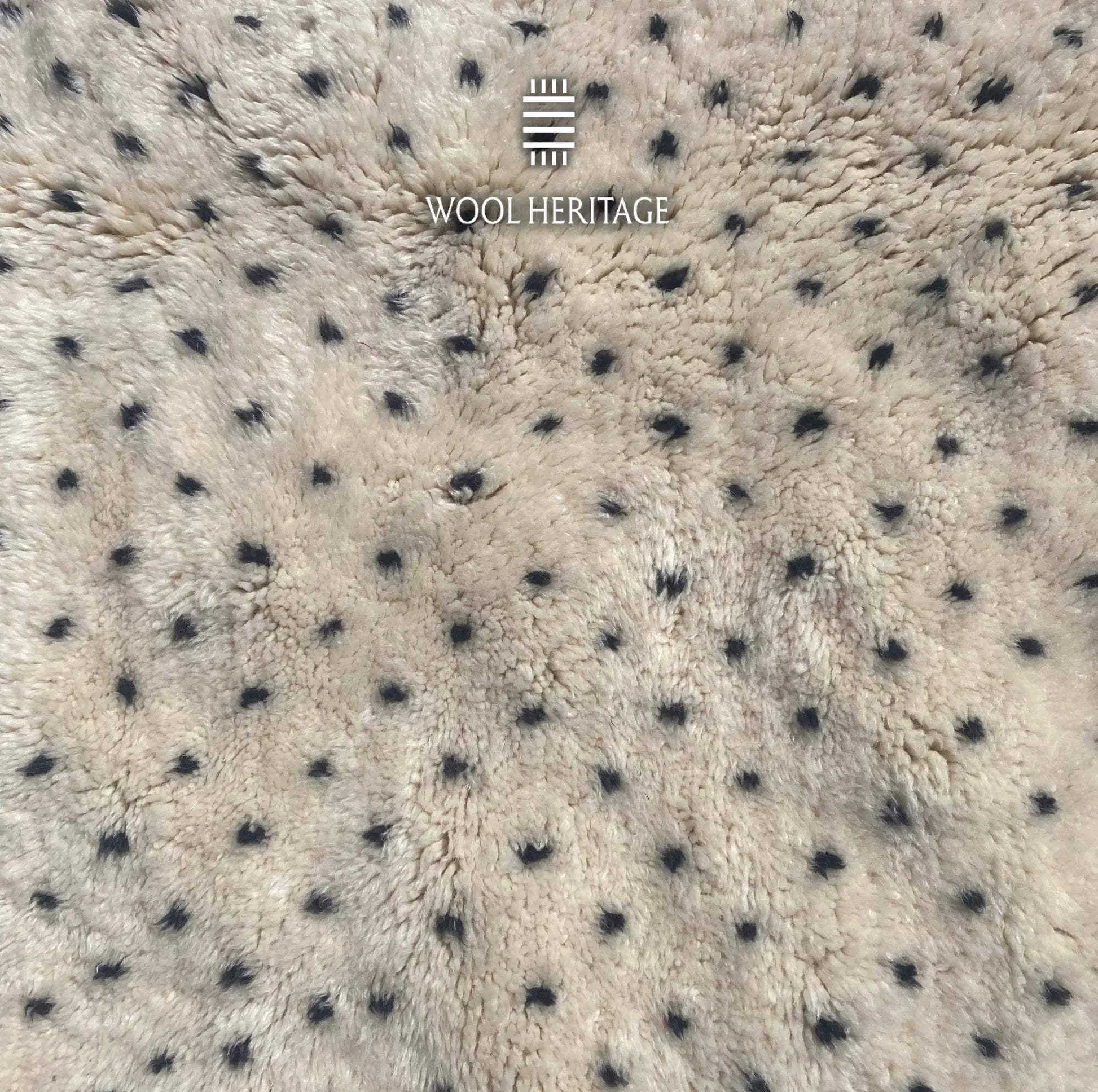 Detailed view of AMUD rug showing varied charcoal dots hand-knotted into the dense ivory wool pile