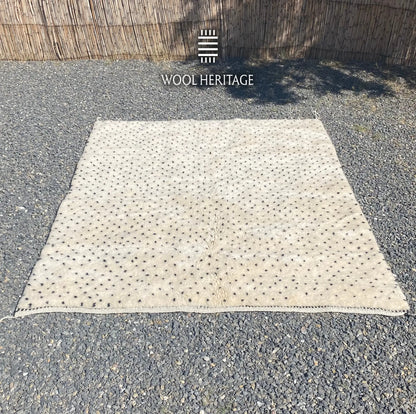 Lengthwise view of AMUD Moroccan rug laid flat, showing its complete dotted seed pattern and ivory field