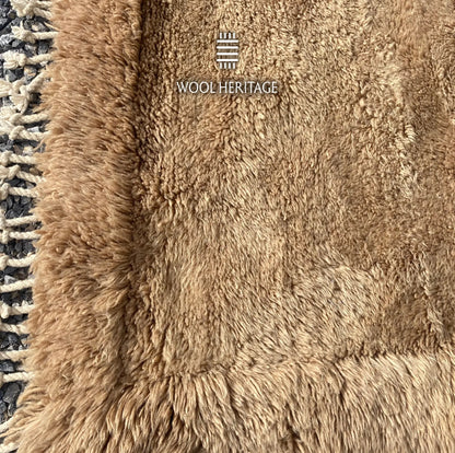 Detailed view of ASIREM high-low rug showing the raised camel border and varied wool pile