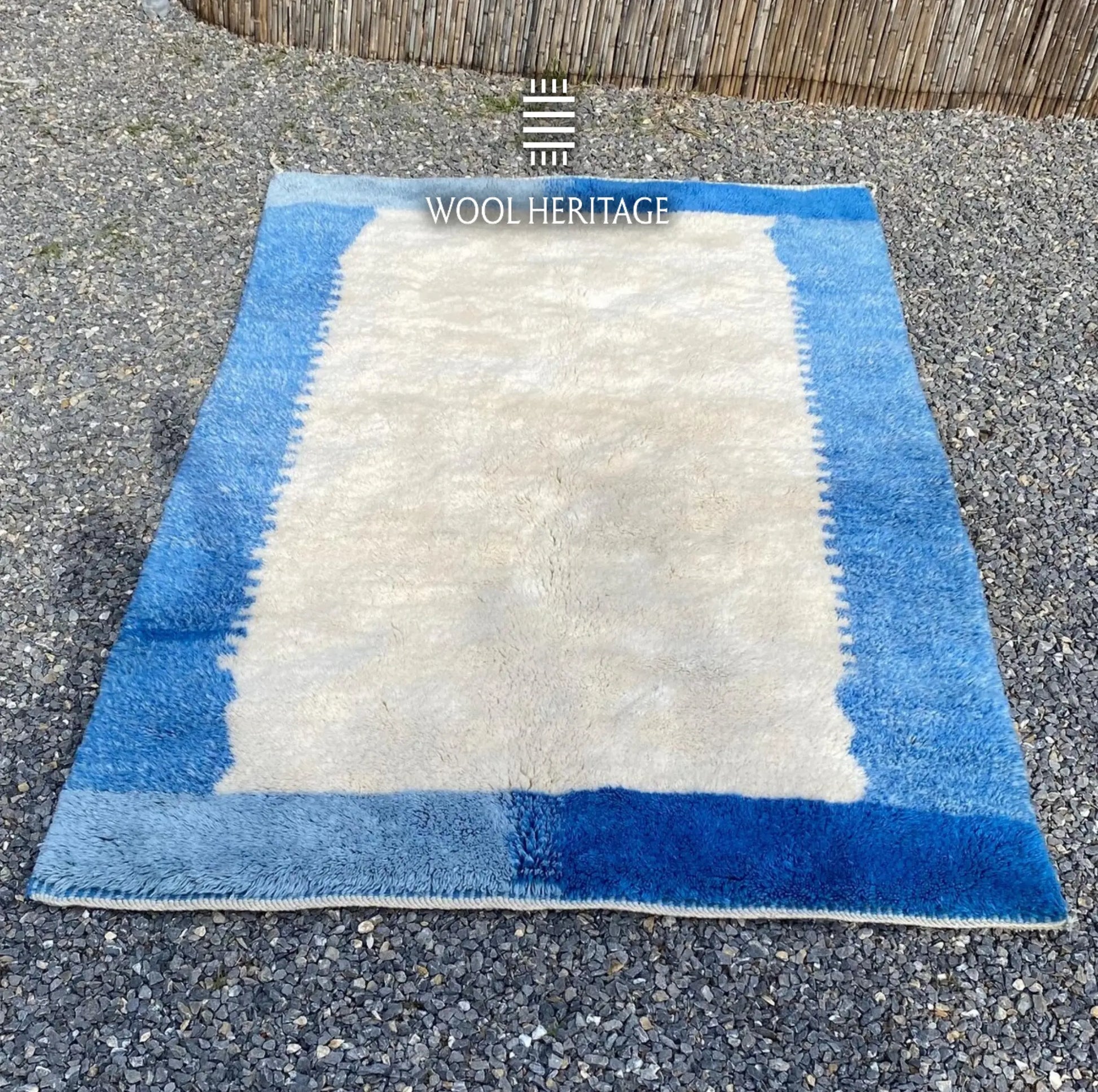 IGENNA Beni Mrirt rug laid flat, showing its open ivory center framed by layered blue colour blocks