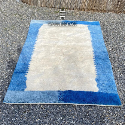 IGENNA Beni Mrirt rug laid flat, showing its open ivory center framed by layered blue colour blocks