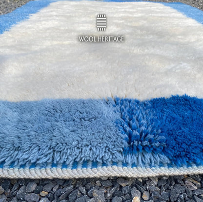 Close-up of IGENNA rug showing its soft ivory pile, sky-blue and cobalt border, and finished edge