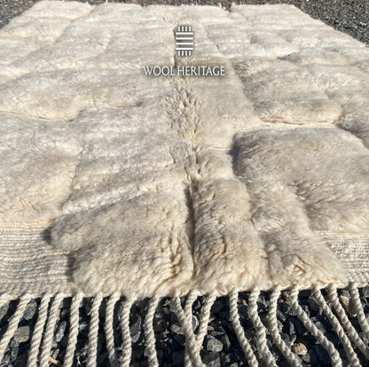 Low-angle view of IGHREM Moroccan wool rug showing the ivory high-low pile and cotton fringe