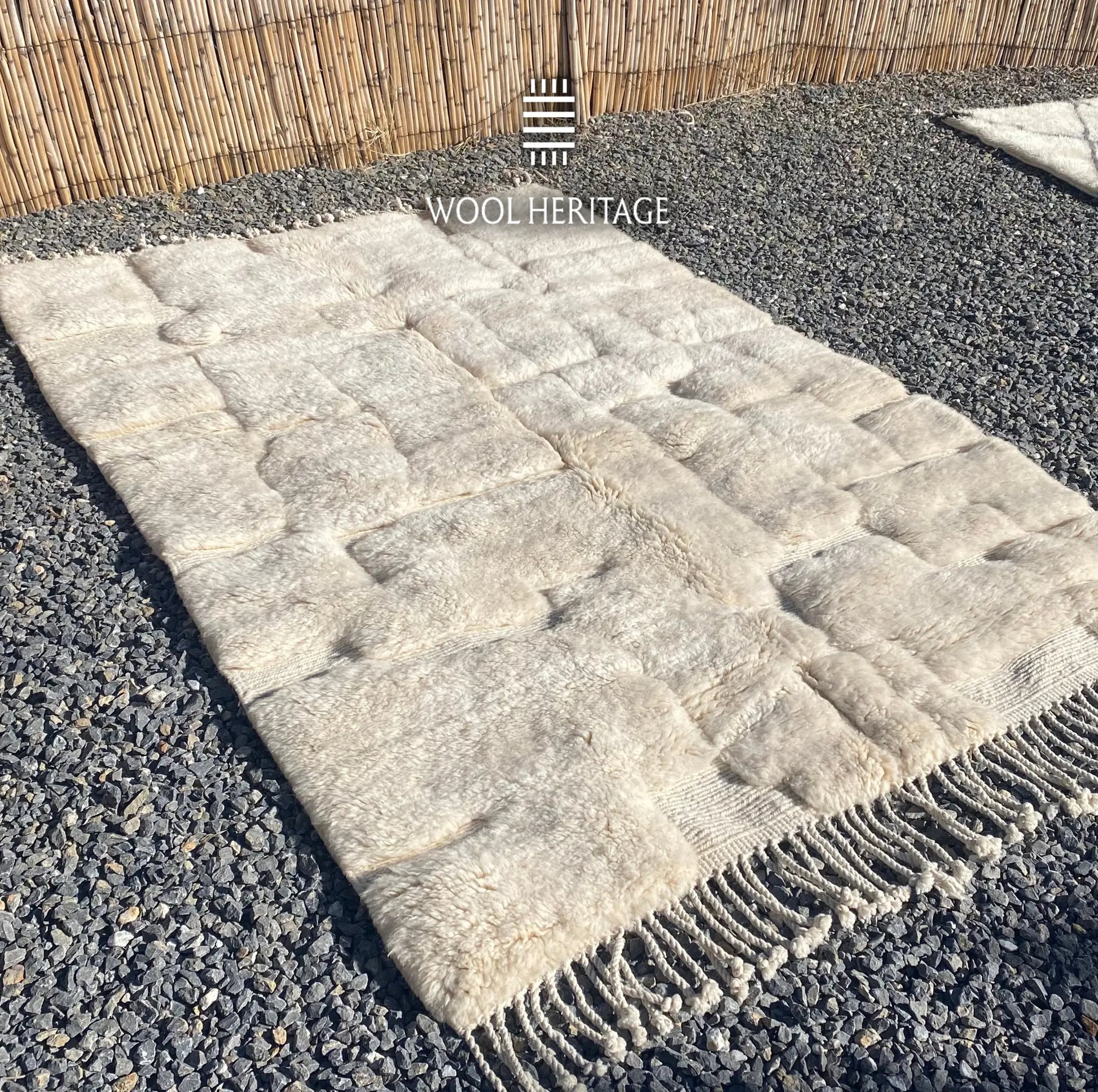 Angled view of IGHREM ivory Beni Mrirt rug showing its sculpted rectangular pattern and fringe