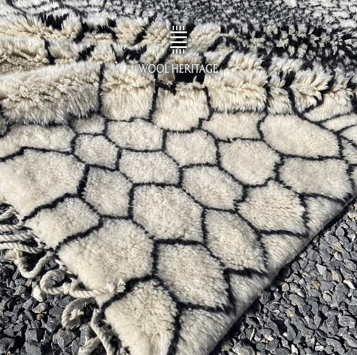 Close-up of an ITRAN rug corner showing the geometric wool pattern and hand-plaited cotton fringe