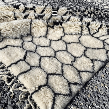 Close-up of an ITRAN rug corner showing the geometric wool pattern and hand-plaited cotton fringe