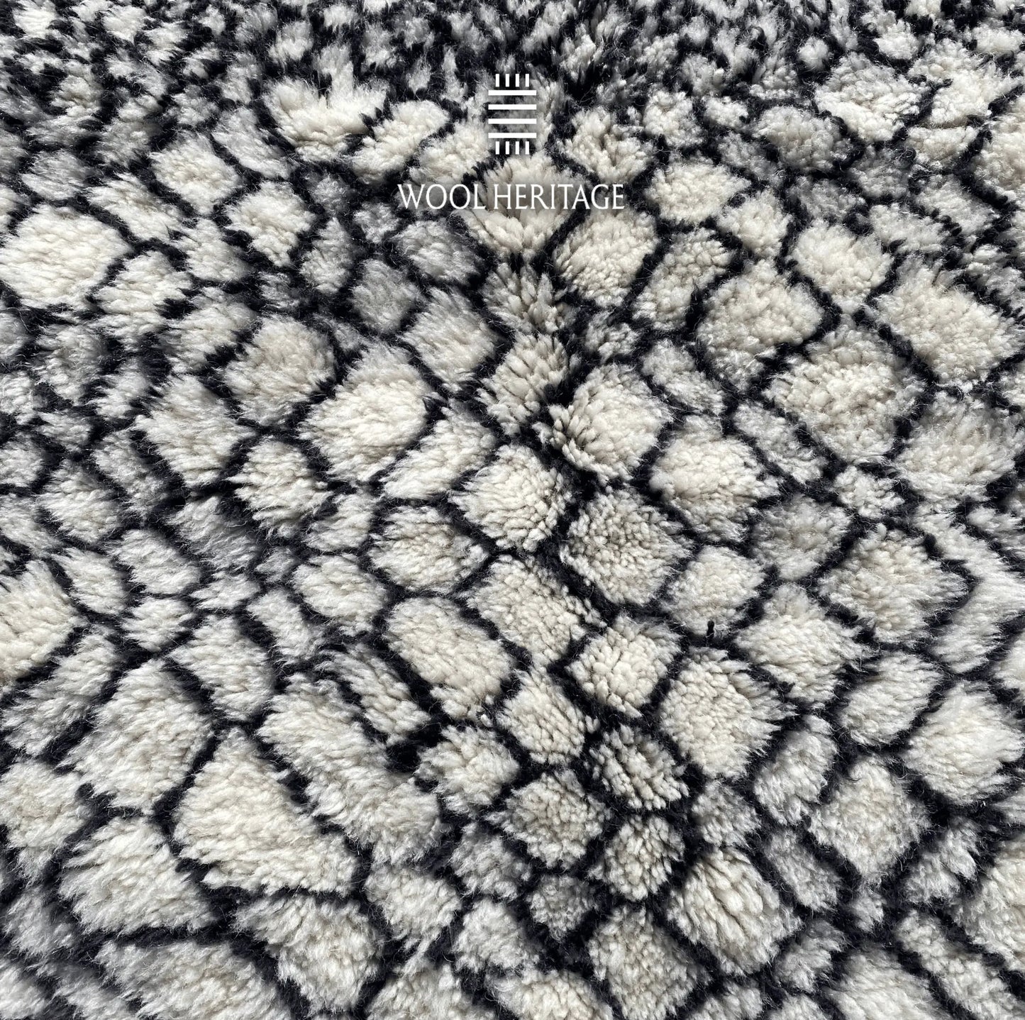 Detailed view of ITRAN rug showing the irregular black diamond lattice across the ivory wool field