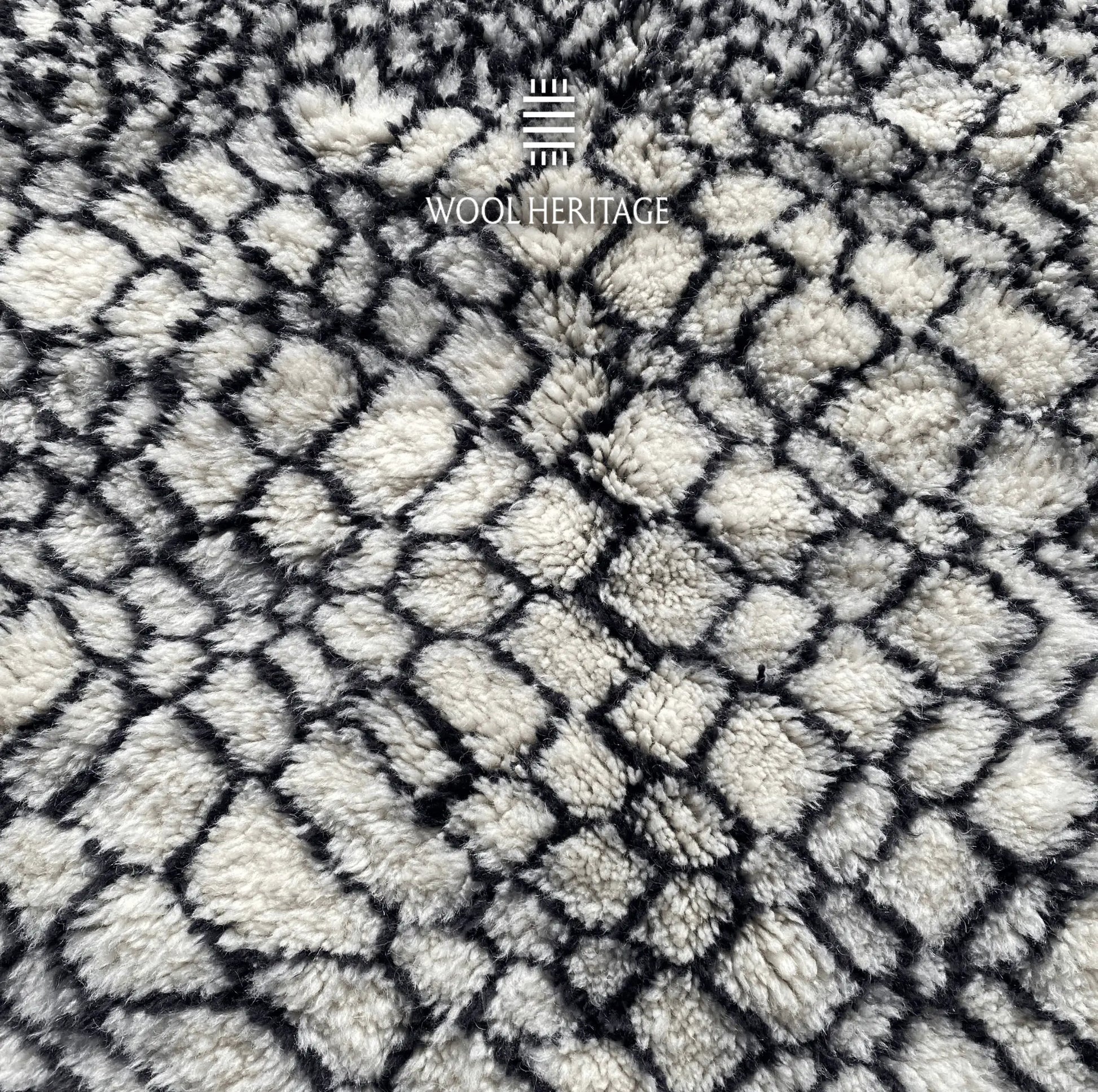 Detailed view of ITRAN rug showing the irregular black diamond lattice across the ivory wool field