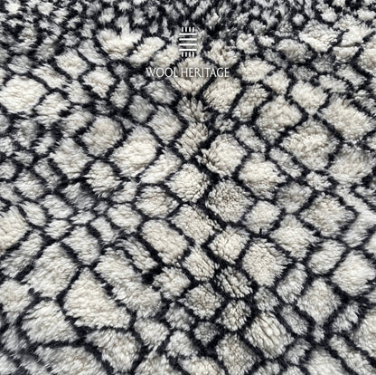 Detailed view of ITRAN rug showing the irregular black diamond lattice across the ivory wool field