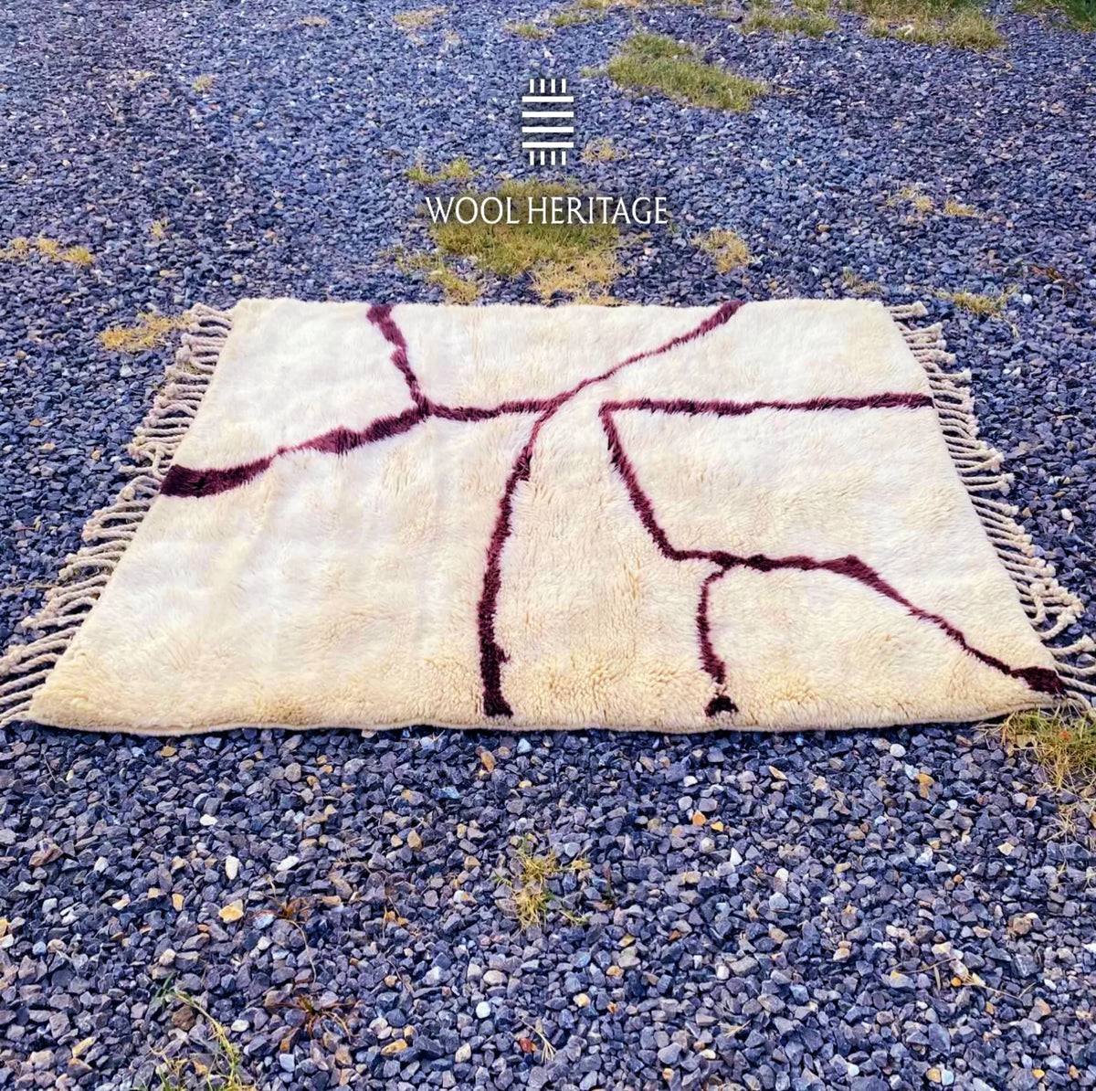 Full horizontal view of IZURAN Moroccan rug showing burgundy branches spreading across the warm ivory field