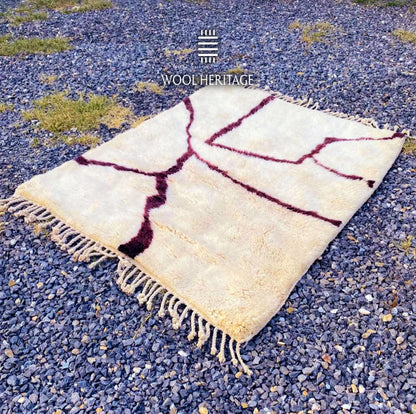 Angled view of IZURAN Moroccan wool rug showing its branching burgundy root pattern and hand-finished fringe