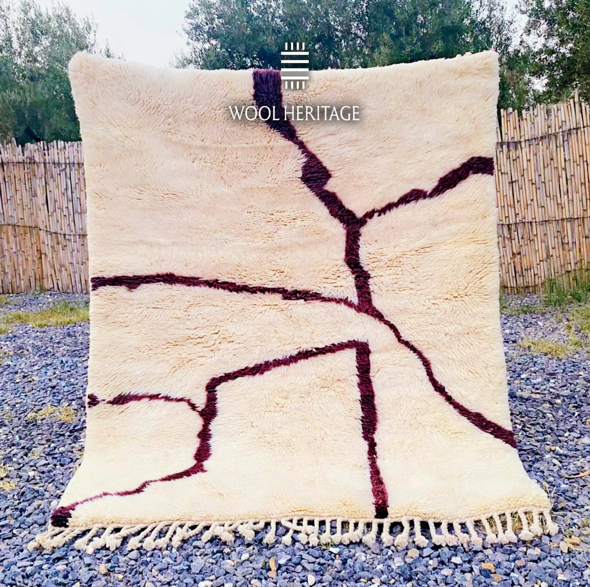 IZURAN hand-knotted ivory and burgundy Moroccan wool rug displayed outdoors in a full front view