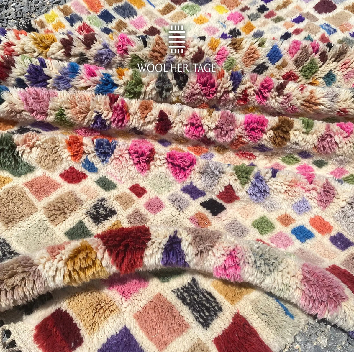 Folded detail of TAFSUT hand-knotted rug showing its colourful high-low wool pile and varied woven marks