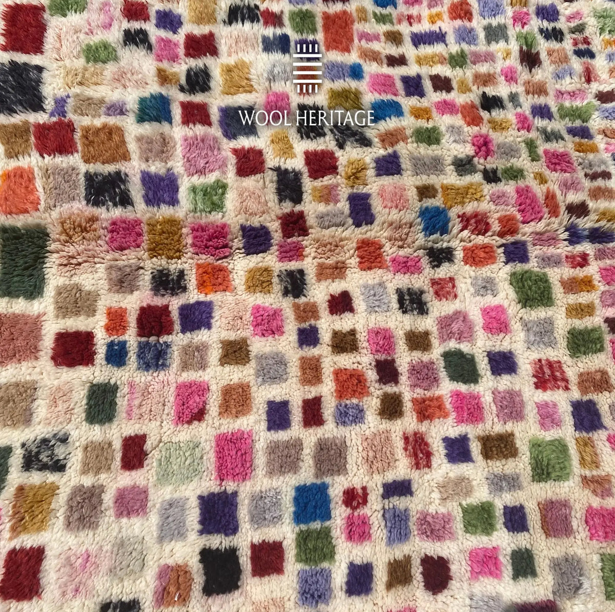 Close-up of TAFSUT rug showing multicolour rectangular marks and the dense ivory wool background
