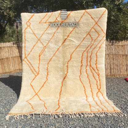 TAFUKT hand-knotted ivory and orange Moroccan wool rug displayed outdoors in a full front view