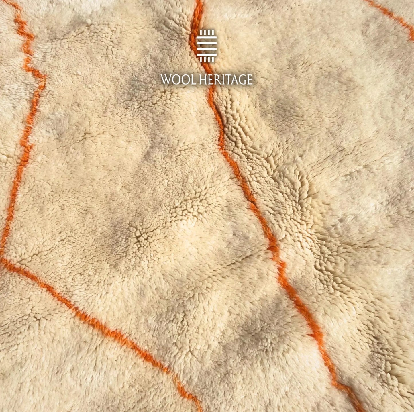 Detailed view of TAFUKT rug showing a warm orange line crossing the soft ivory Moroccan wool pile