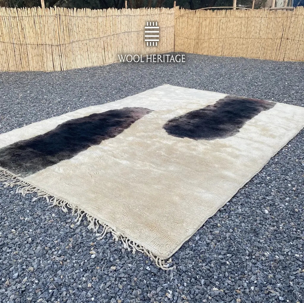 TAFUNAST Beni Mrirt rug laid flat, showing its two charcoal cattle-inspired forms across an ivory field