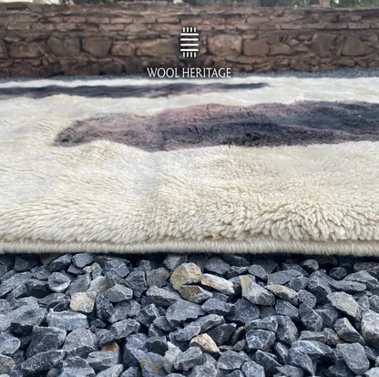 Close-up of TAFUNAST rug showing the dense ivory wool pile, charcoal pattern, and hand-finished edge