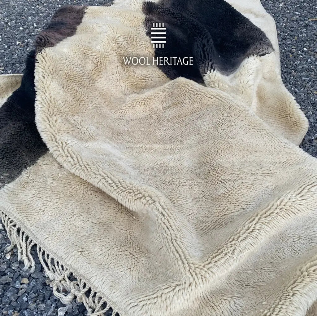 Folded detail of TAFUNAST rug showing its soft ivory and charcoal Moroccan wool pile