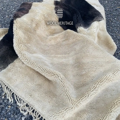 Folded detail of TAFUNAST rug showing its soft ivory and charcoal Moroccan wool pile