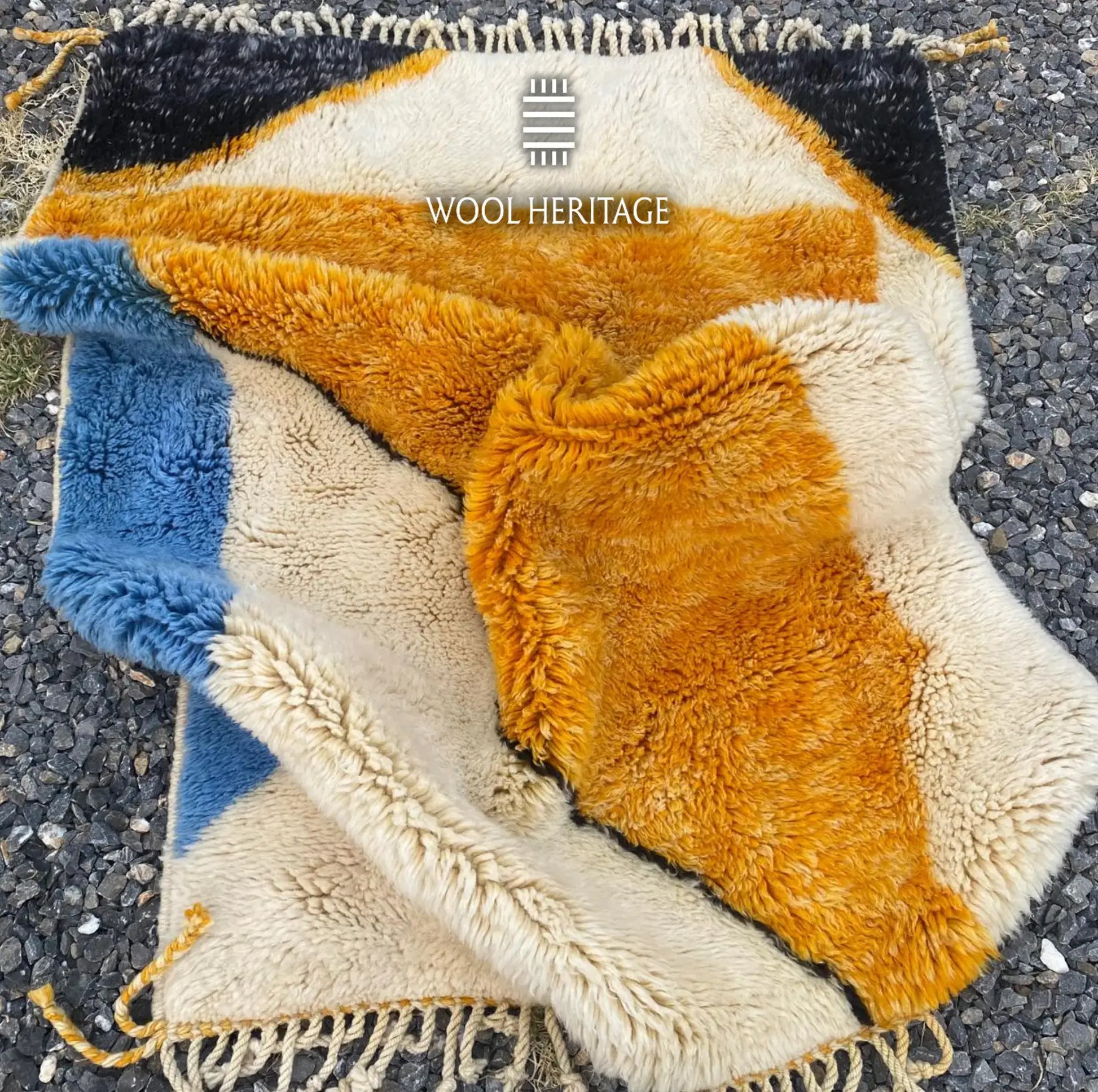 Folded detail of TAMURT Beni Mrirt rug showing its thick wool pile, organic colour fields, and fringe finish