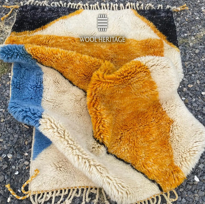 Folded detail of TAMURT Beni Mrirt rug showing its thick wool pile, organic colour fields, and fringe finish