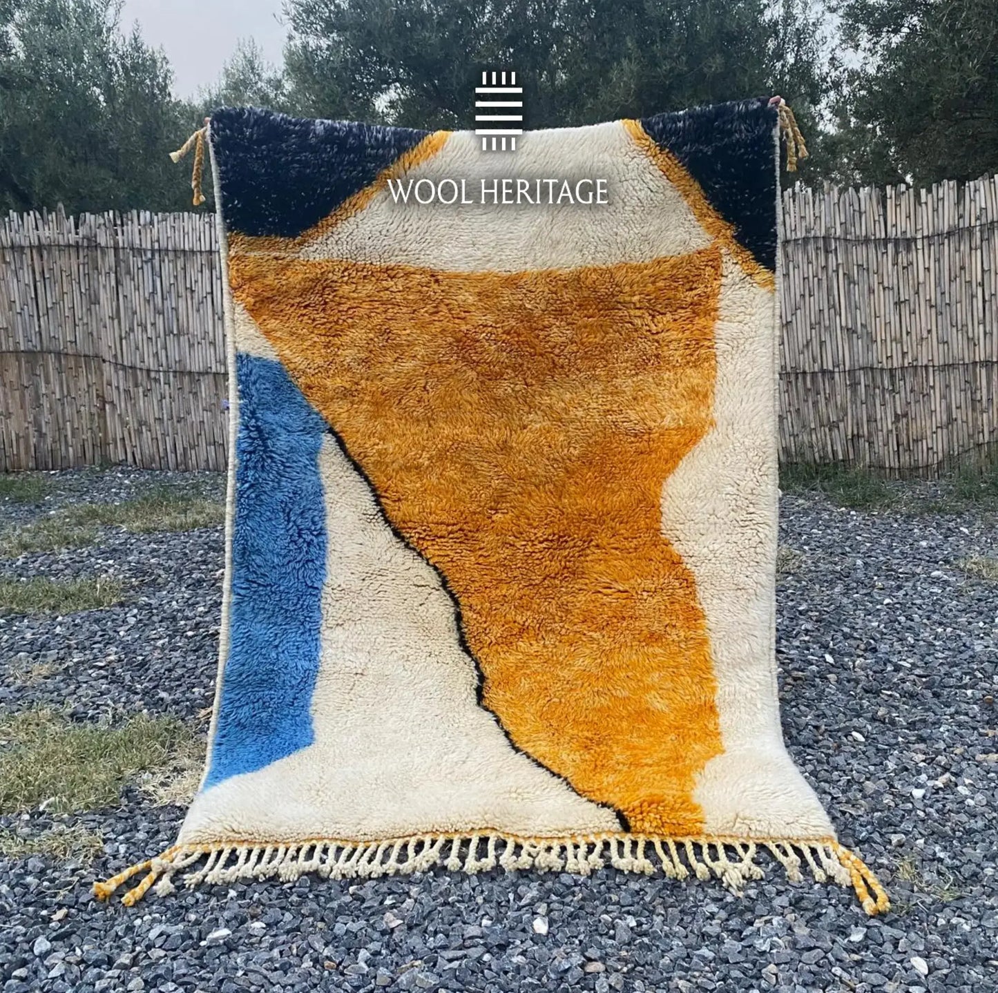TAMURT hand-knotted Moroccan wool rug displayed outdoors in a full front view with ochre, ivory, navy, and blue forms
