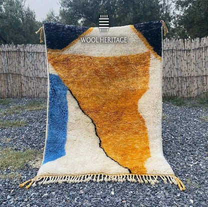 TAMURT hand-knotted Moroccan wool rug displayed outdoors in a full front view with ochre, ivory, navy, and blue forms