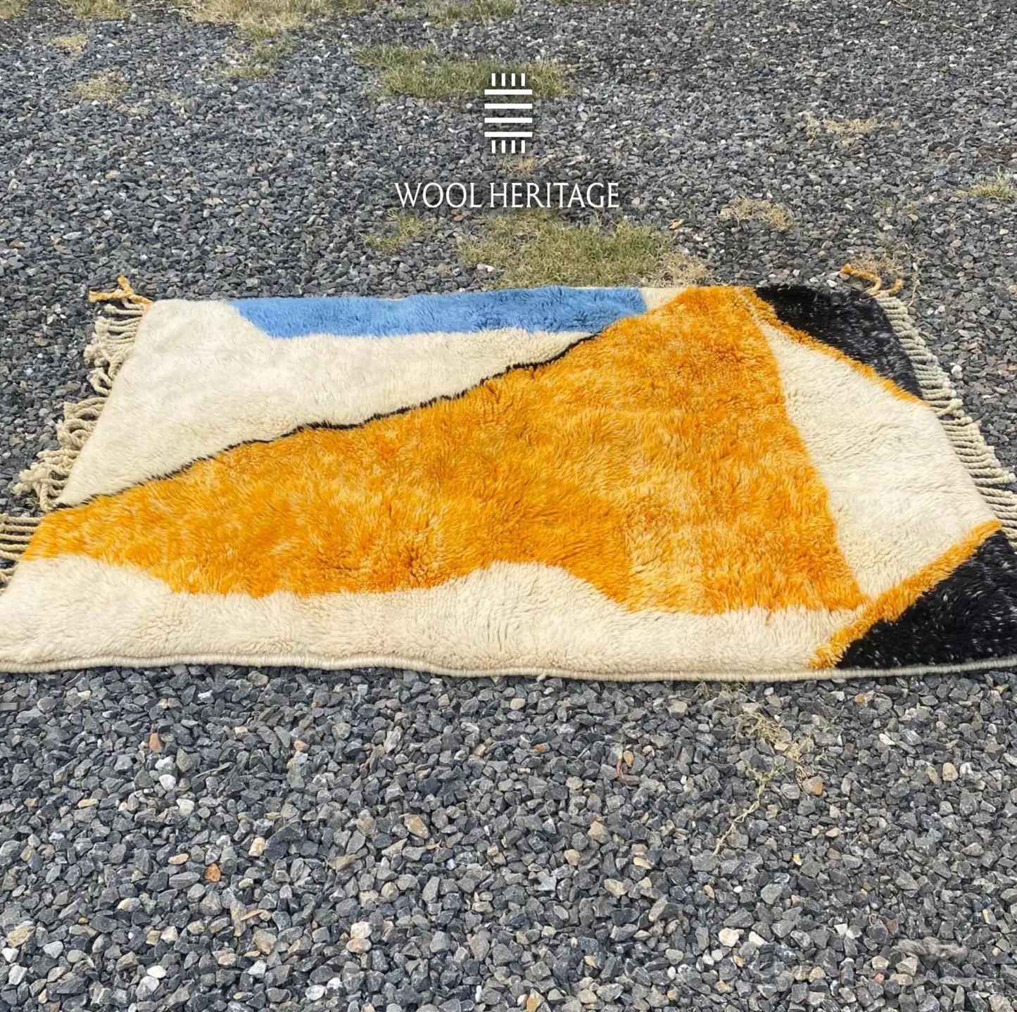 Folded TAMURT Moroccan rug showing the meeting of its ochre, ivory, blue, and deep navy wool sections
