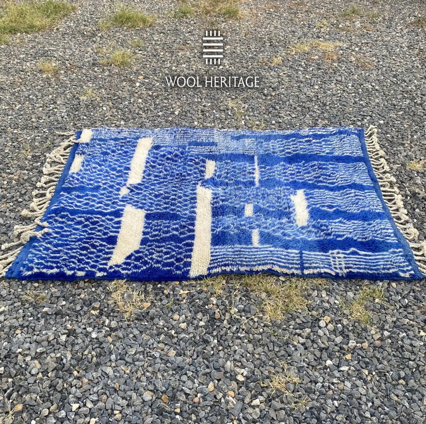 Full horizontal view of TARGA Moroccan wool rug showing broken ivory bands across its patterned blue field