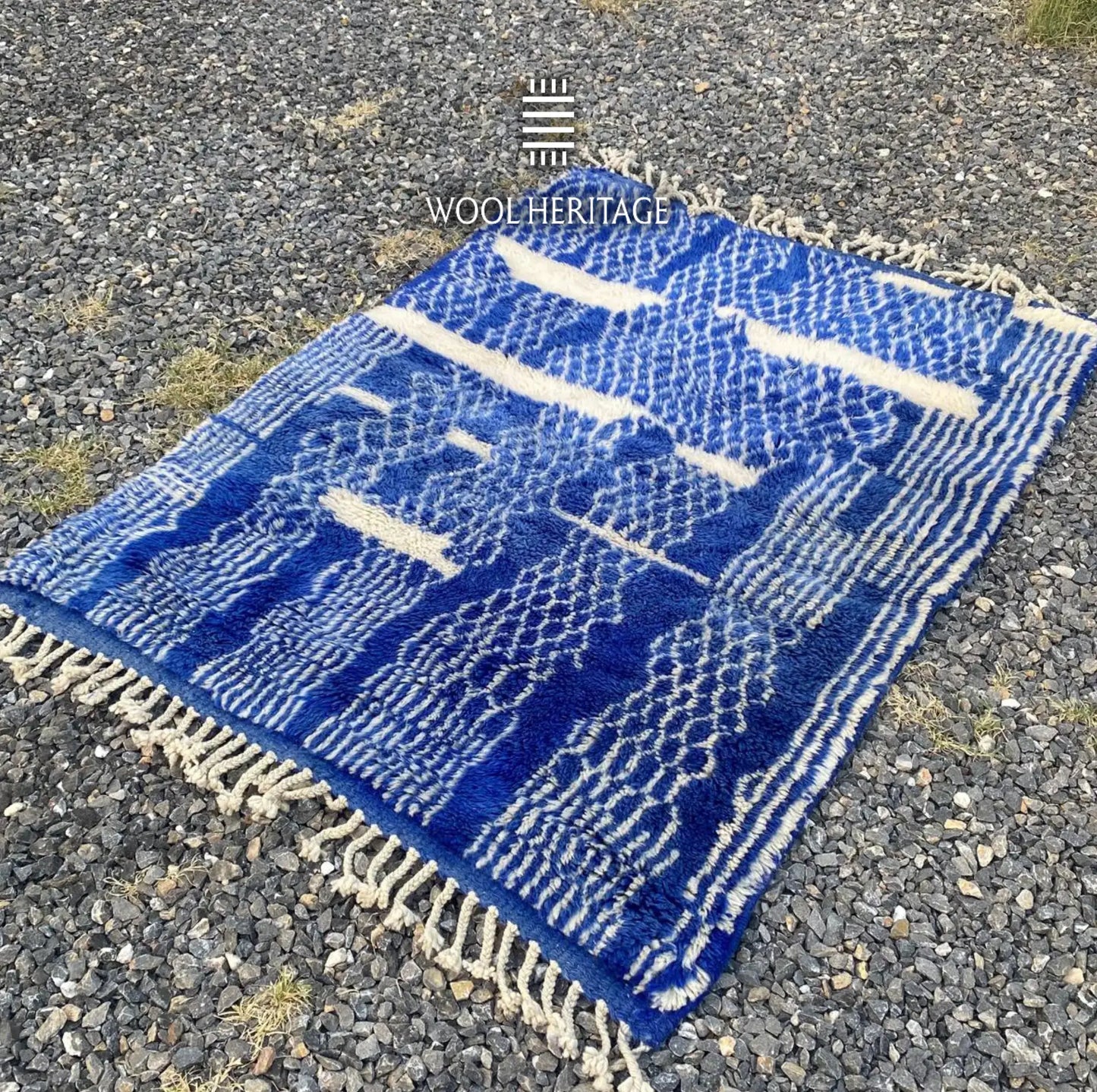 Angled view of TARGA Moroccan rug showing its ivory pathways, layered blue patterns, and hand-finished fringe