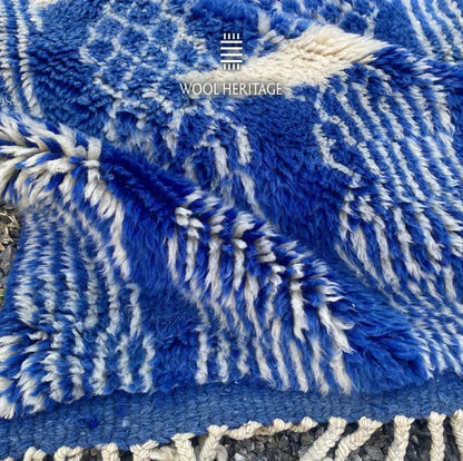 Folded detail of TARGA hand-knotted rug showing layered blue patterns, thick wool pile, and fringe finish