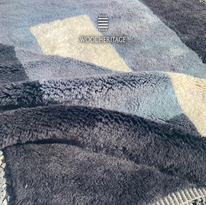 Folded detail of TAWWURT hand-knotted rug showing its thick navy, pale blue, and ivory wool pile