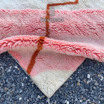 Folded detail of TAYRI hand-knotted rug showing the terracotta line crossing the pink and ivory wool sections