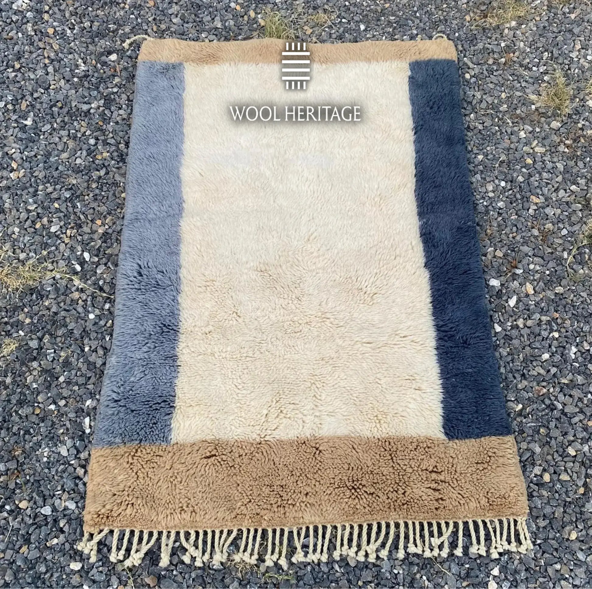 TIFAWT Beni Mrirt rug laid flat, showing its minimalist ivory center and asymmetrical blue borders