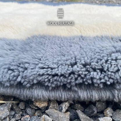 Close-up of TIFAWT rug showing the soft ivory and slate-blue Moroccan wool pile and finished edge