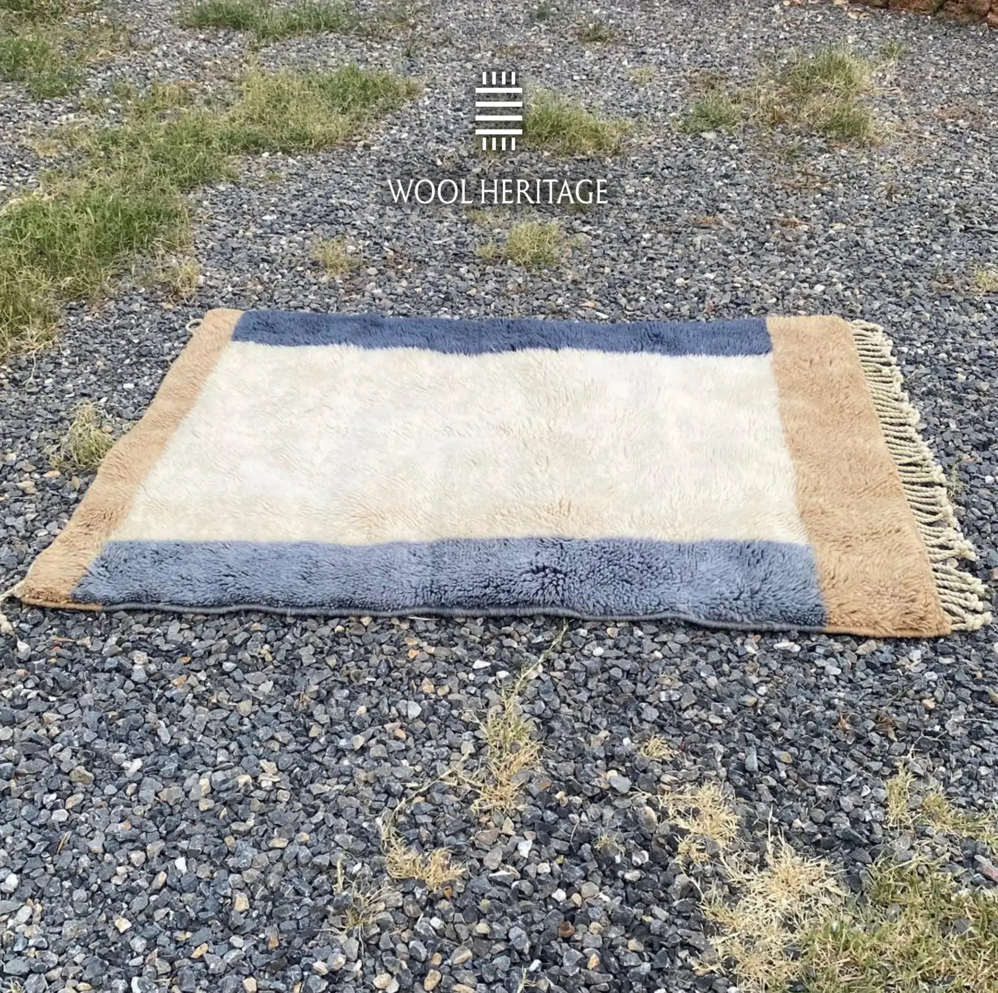 Full horizontal view of TIFAWT Moroccan wool rug showing the ivory field framed by blue and beige bands