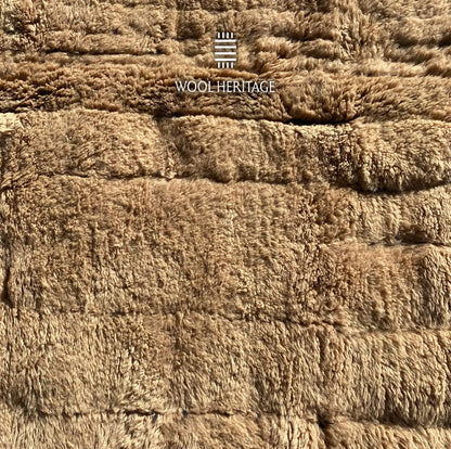Close-up of TIRRA rug showing abstract raised forms and recessed markings across the wool pile