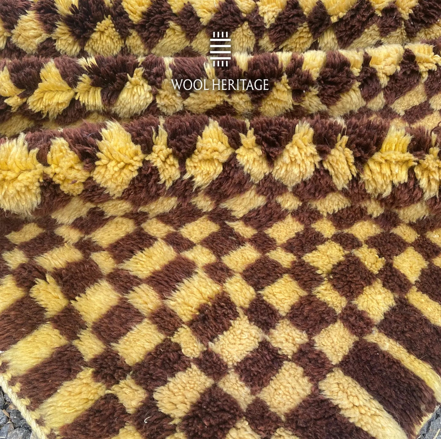 Detailed view of the TIZWIT rug edge showing its hand-knotted golden and brown wool texture