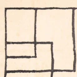 Handwoven abstract beige Moroccan rug with black line grid pattern, crafted in natural wool by Beni Mrirt artisans.